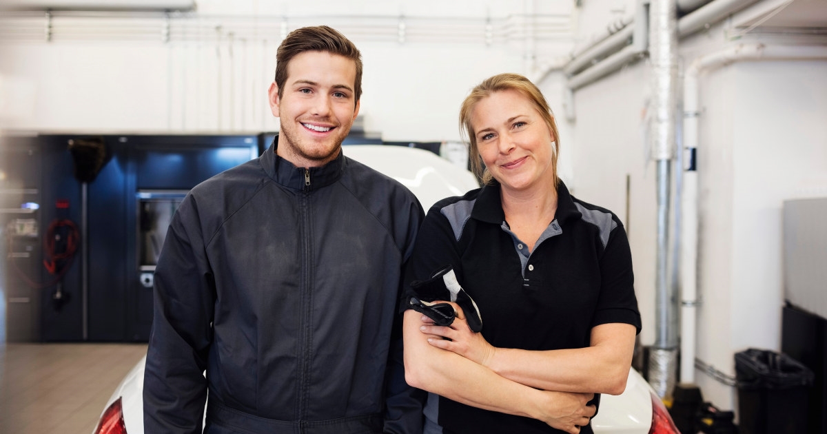 ung kvinnelig og mannlig mekaniker smiler på jobb