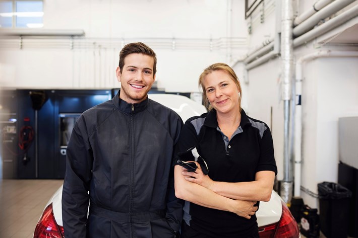 ung mannlig og kvinnelig mekaniker smiler på verksted